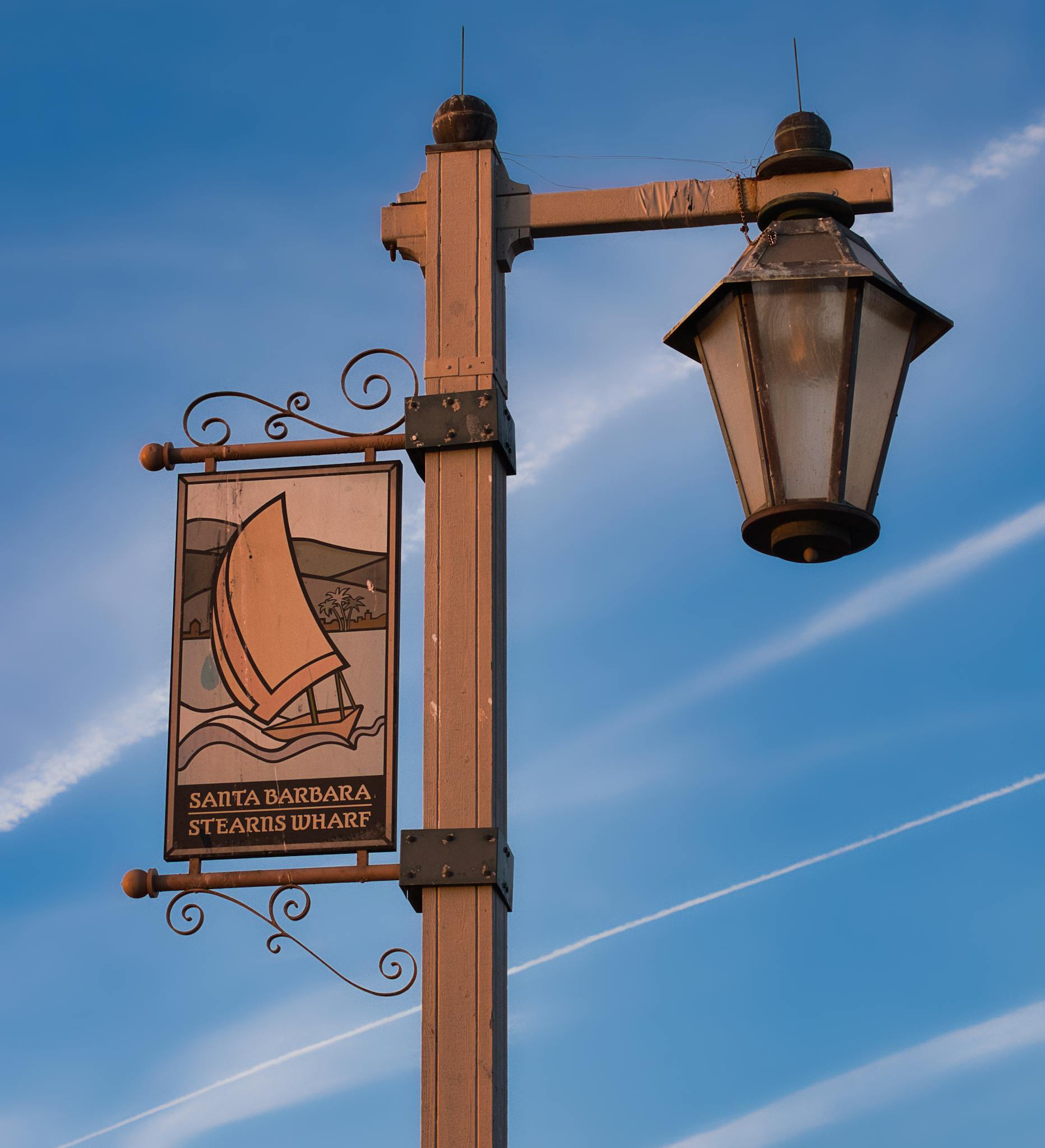 Street lamp and Stearns Wharf sign against a clear blue sky in Santa Barbara, California.